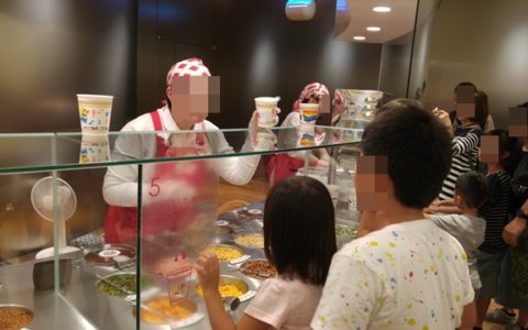 カップヌードルミュージアムのチキンラーメンファクトリーで説明員の方の説明を熱心に聞く子どもたち。